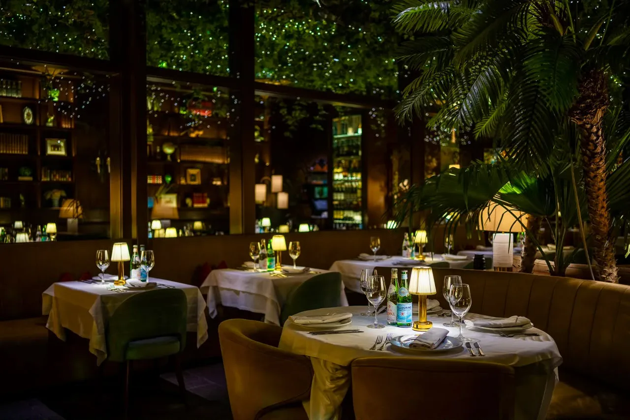 Sal&oacute;n de noche con l&aacute;mparas y palmeras